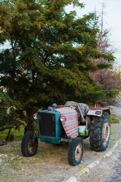 old tractor covered with cloth parked on the road - agricultural machinery retro revival summer farm imagens e fotografias de stock