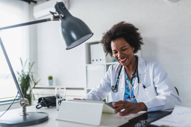 african american woman doctor working at her office doing telemedicine services. helping patients online and by the phone. primary care consultations - african descent customer service representative computer service imagens e fotografias de stock