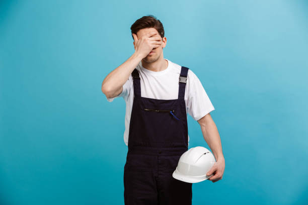 istock Confused male builder holding protective helmet while covering his eyes 1290683637