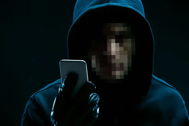 Portrait of unrecognizable hacker with smartphone