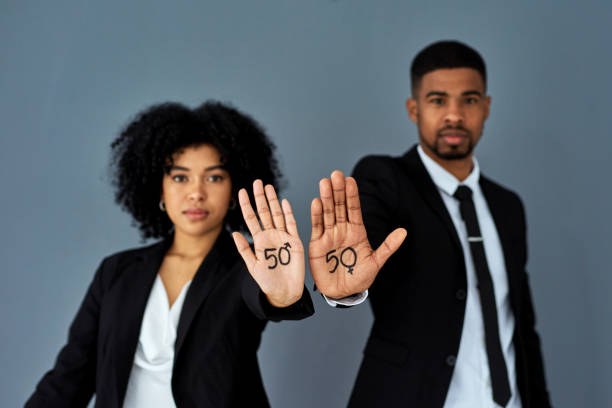 Can we close the gap? Yes we can Shot of businessman and businesswoman advocating for gender equality against a grey studio background equality stock pictures, royalty-free photos & images