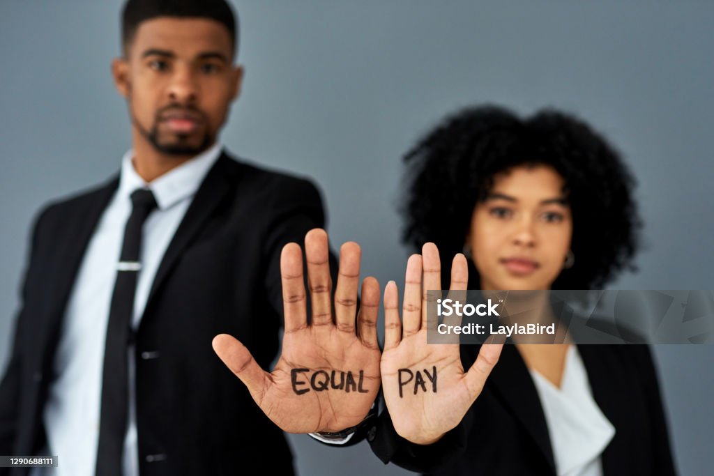 I shouldn't have to earn more because of my gender Shot of a businessman and businesswoman advocating for equal pay against a grey studio background Wages Stock Photo