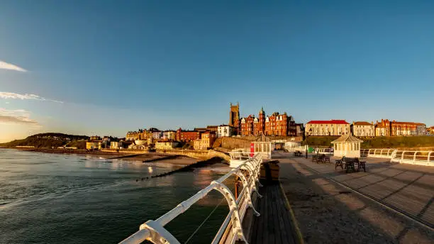 Fisheye view of the town of Cromer in Norfolk captured from the wooden boardwalk of the Victorian pier at sunrise. Intentional distortion and curvature