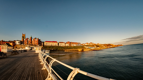Fisheye view of the seaside town of Cromer captured during sunrise from the wooden boardwalk of the Victorian pier. Intentional distortion and curvature