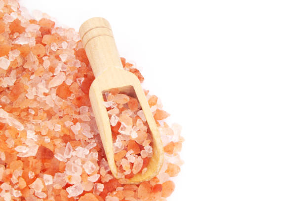 Himalayan pink salt and wooden scoop isolated on white background, space for text