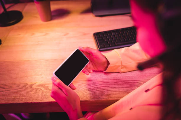 Smartphone with blank screen in hands of gamer on blurred foreground