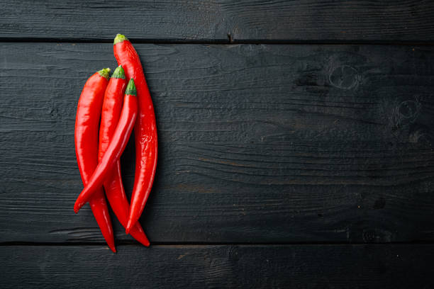 istock Raw red chili pepper, on black wooden table, flat lay with space for text 1290691798