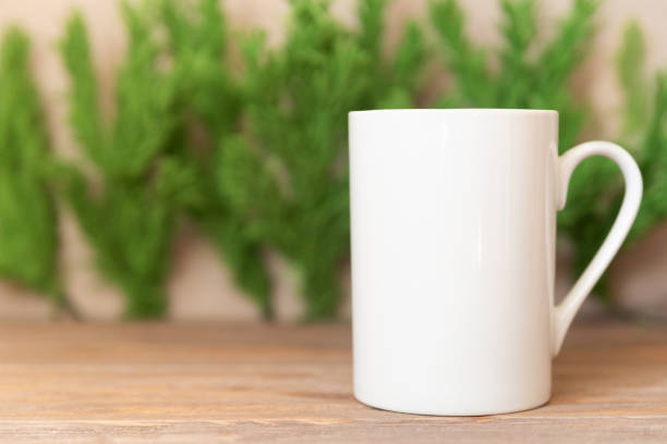 istock Mockup - White cup on Christmas tree branches background. Coffee or tea mug for your design 1290693156
