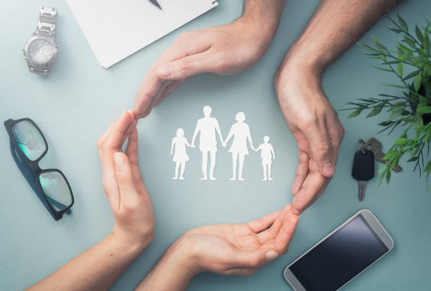 Family care concept. Hands with paper silhouette on table. Hands with cut out paper silhouette on table. Family care concept. life insurance stock pictures, royalty-free photos & images