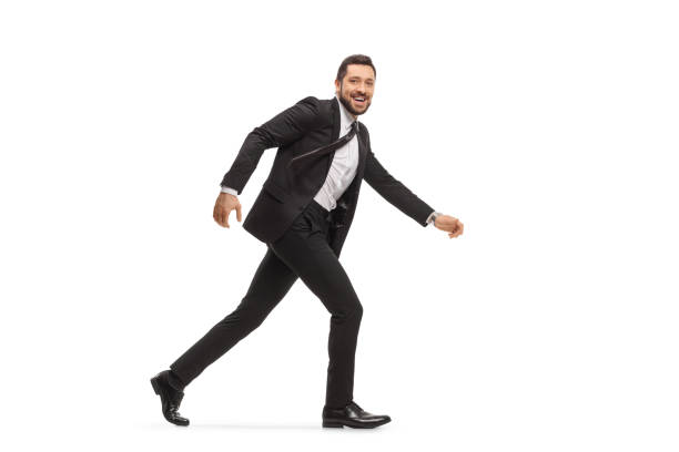 istock Handsome man in a black suit running and looking at camera 1290693485