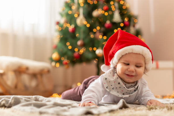 istock Baby boy wearing Santa hat playing by the Christmas tree 1290693603