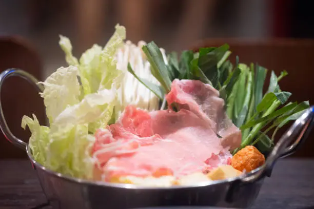 Photo of Shabu Shabu or Sukiyaki, a popular dish of pork, beef and fresh vegetables. Placed on a table with a boiling pot boiling in a Japanese restaurant.