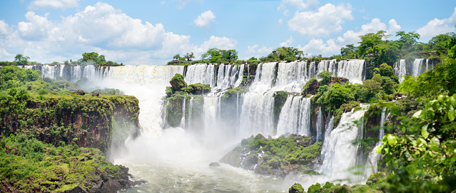 Scenic view of the breathtaking Iguazu Falls crashing onto rocks in the rainforest on a sunny day