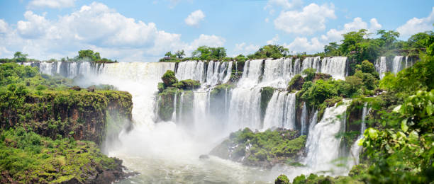 Scenic view of the majestic Iguazu Falls Scenic view of the breathtaking Iguazu Falls crashing onto rocks in the rainforest on a sunny day eco tourism photos stock pictures, royalty-free photos & images