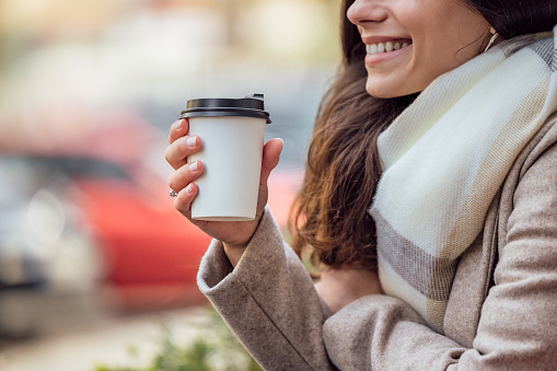 Portrait of smiling woman, focus on cup of hot drink.