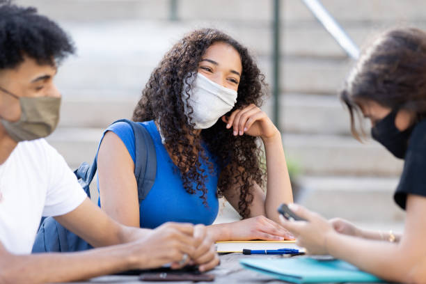 istock College students wearing masks talking together 1290697187