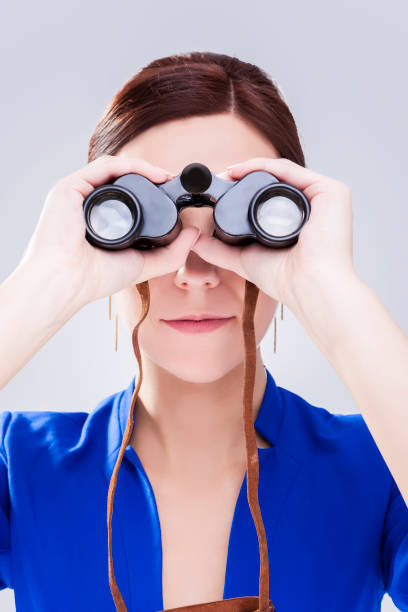 istock Information Search Concepts. Caucasian Brunette Female Posing With Binoculars as a Concept of Search.Vertical image 1290699984