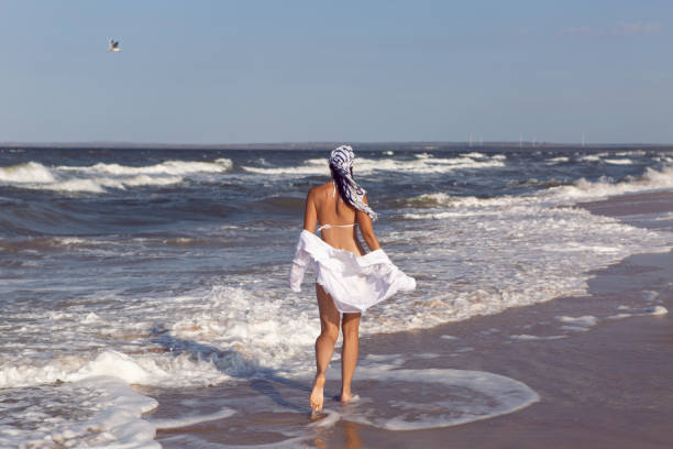 istock woman run in a white bathing suit and hat sunglasses on an empty sandy beach 1290701059