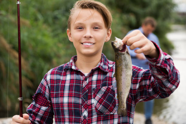 istock Boy holding catch freshwater fish in hands on forest 1290702296