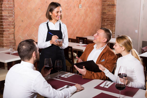 istock Positive female waiter writing down order 1290702341