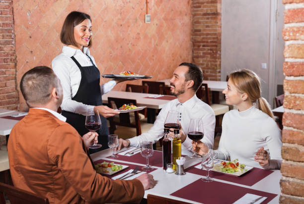 istock Female waiter bringing order to visitors 1290702344