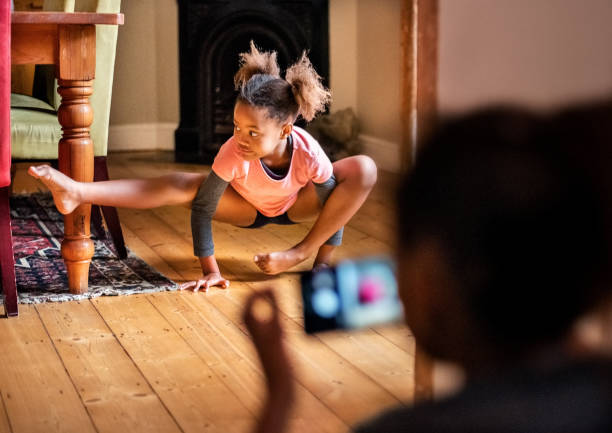 Small girl doing yoga at home Small girl doing yoga at home with her sister taking her pictures with a mobile phone leanincollection stock pictures, royalty-free photos & images