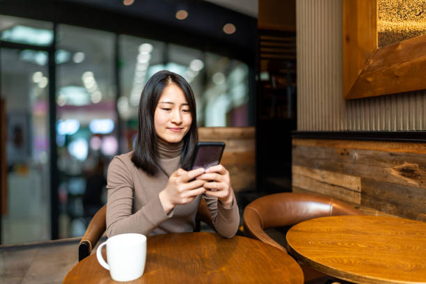 istock Young Asian woman using smart phone in the coffee shop 1290704433