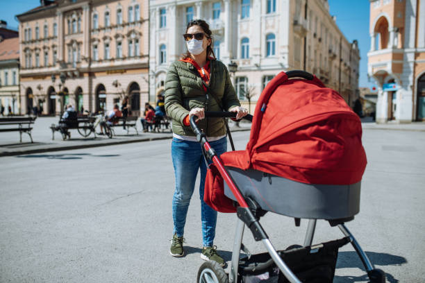 istock Woman with face mask outdoors, pushing baby pram 1290704771