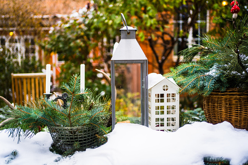 table in the yard of a country house with New Year's decoration covered with snow. coniferous branches, decorative lanterns for the festive mood.