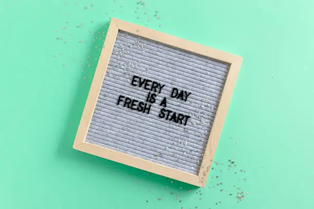 Letterboard with quote Every day is a fresh start and silver stars on mint background