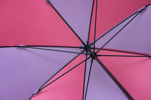 Inside shot of open colorful umbrella with black metal spoke and pole.