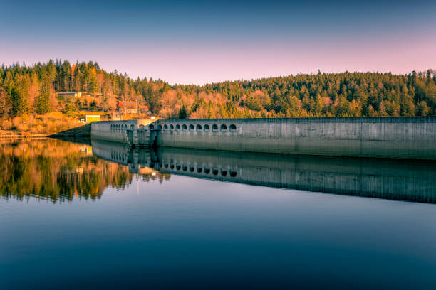 Sec water reservoir with concrete dam and wintertime snowy hills of Iron Mountains around. Czechia. Aerial view from drone.. Black and white image.