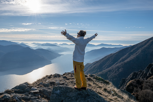 He embraces nature, mountains and lake in distance
