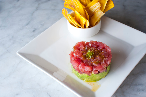 Tuna tartare. Classic American restaurant or bistro appetizer classic. Sushi grade ahi tuna, diced, mixed with eggs, red onions, olive oil, lemon juice, garlic and capers. Served with garlic bread.