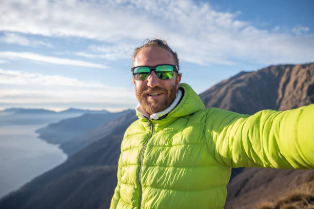 istock Young man on mountain top takes selfie at sunrise 1290720857