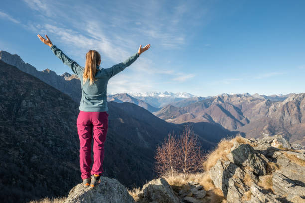 istock Hiker stands arms out on mountain top 1290721159