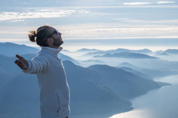 istock Hiker stands arms out on mountain top 1290721281