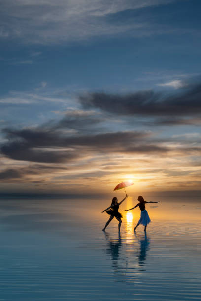 Ballerinas dancing on water at sunset