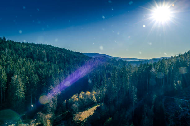Germany, Sunrise light on beautiful schwarzwald mountains snow covered cold winter morning panorama view above tree tops blue sky