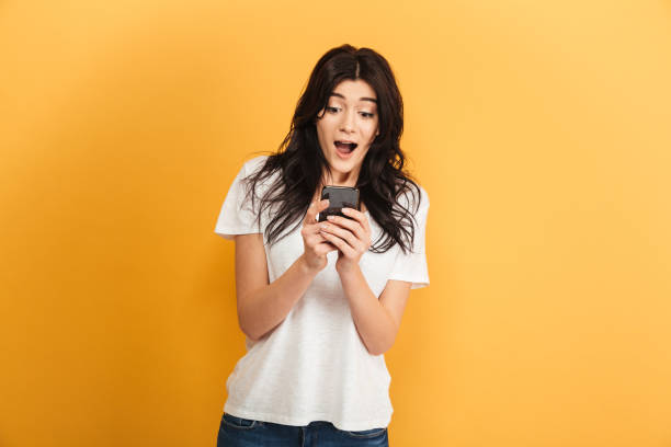 istock Emotional cute young pretty woman using mobile phone looking aside. 1290723577