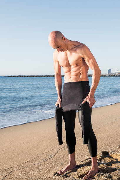 istock Swimmer putting on his wetsuit. Sand, beach, neoprene. 1290724759