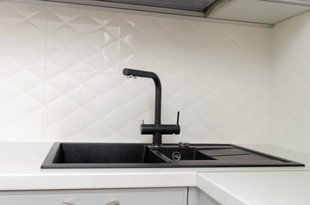 istock Black sink with faucet in light, white classic kitchen close-up 1290725103