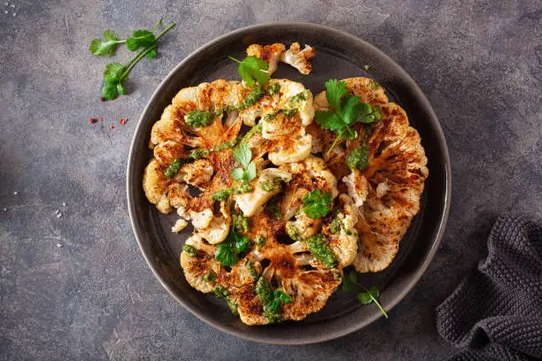 Photo of cauliflower steaks with herb sauce and spice. plant based meat substitute