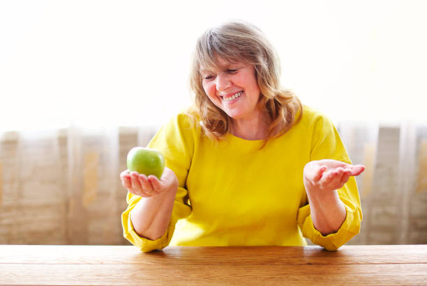 istock Cheerful mature woman with green apple 1290730264