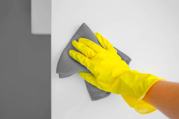 istock A female hand in yellow rubber gloves wipes a modern white kitchen with a microfiber cloth. 1290734936