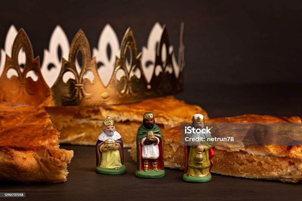 King cake or galette des rois in French. Traditional epiphany pie with golden paper crown and charm King cake or galette des rois in French. Traditional epiphany pie with golden paper crown and tiny charms Epiphany - Religious Celebration Stock Photo