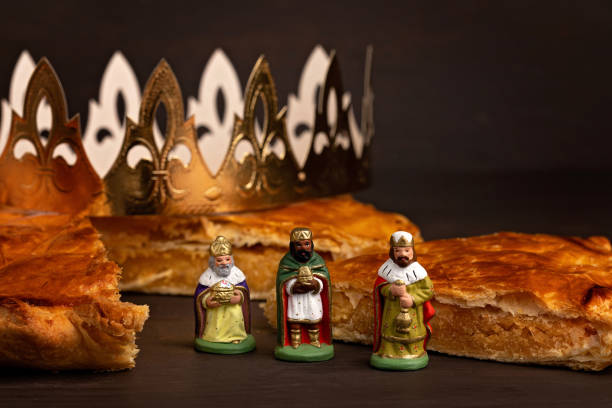 King cake or galette des rois in French. Traditional epiphany pie with golden paper crown and charm King cake or galette des rois in French. Traditional epiphany pie with golden paper crown and tiny charms galette stock pictures, royalty-free photos & images