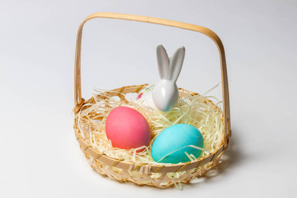 istock Easter eggs and bunny in a basket isolated on white background. 1290741942