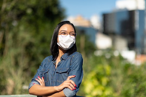 City life and portrait image of a woman smiling behind a protective face mask
