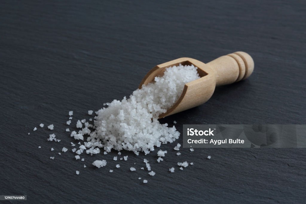 Flower of salt of Guerande - France. Crystals of natural higth quality sea salt from Guerande - France harvested by hand and named "Fleur de sel" in a wooden spoon on the slate surface. Salt - Seasoning Stock Photo